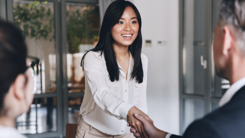 Glad farmaceut skakar hand med sin framtida arbetsgivare efter en lyckad intervju. 