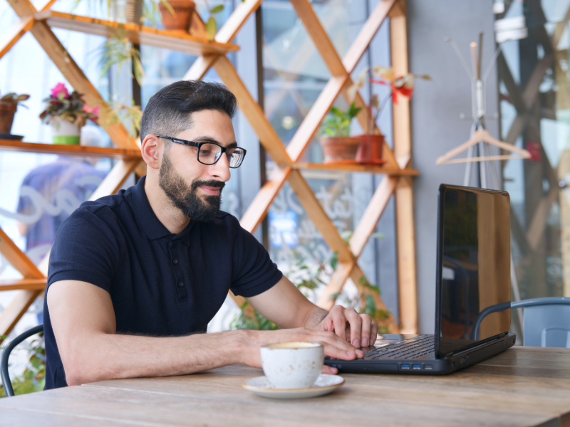 Man framför sin dator med en kaffekopp, betalar räkningar