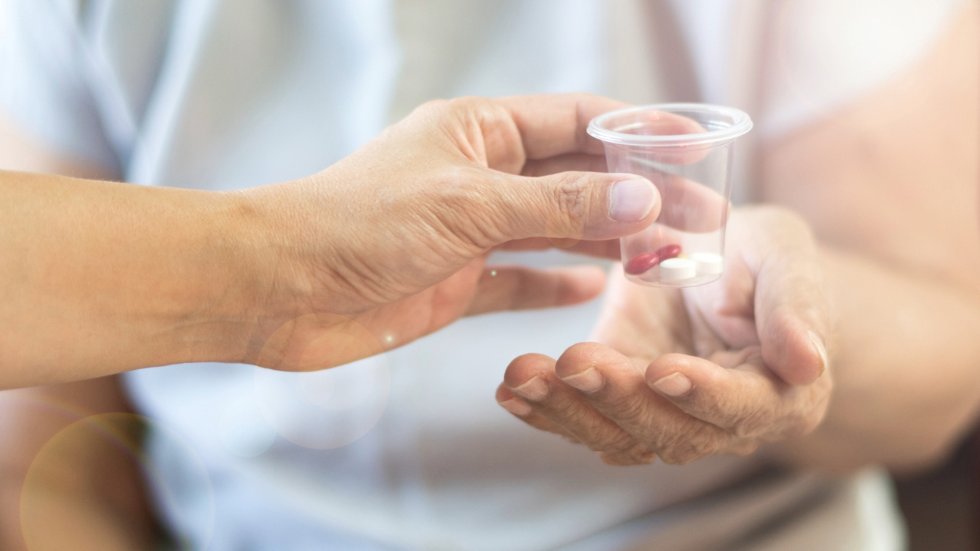 En äldre person får en genomskinlig mugg med läkemedel från en farmaceut